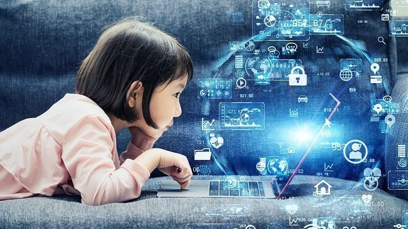 A little girl is getting the most out of technology as she looks at a laptop with a lot of icons on it.