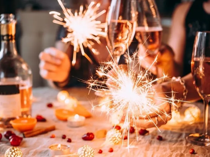 A group of people holding sparklers and ringing in the Cyber-Year at a table.