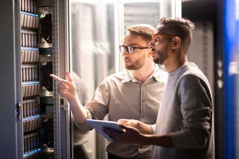 Two men looking at a server in a data center while discussing their co-managed IT services.