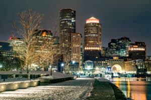 Boston skyline at night with a dusting of snow covering the ground.