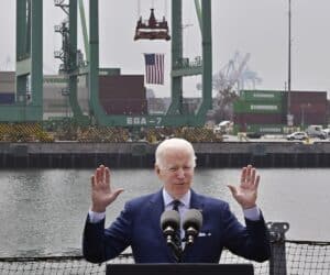 Joe Biden speaks at a podium in front of an American port.