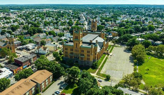 Aerial view of a large Gothic-style building in an urban neighborhood, surrounded by residential houses, trees, and streets on a clear day with managed IT services in Bristol seamlessly integrating technology into the historic landscape.
