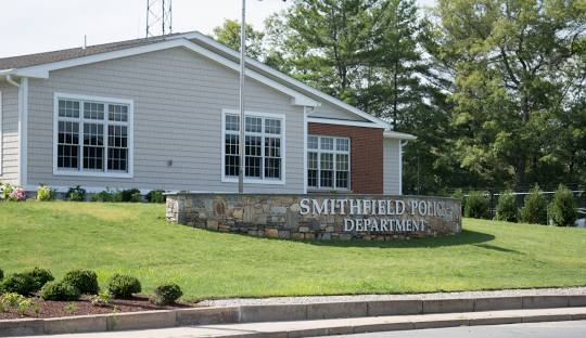 Single-story building labeled "Smithfield Police Department" with a stone sign and manicured lawn in front, surrounded by trees, reflecting the community's commitment to excellence much like the local managed IT services Smithfield offers.