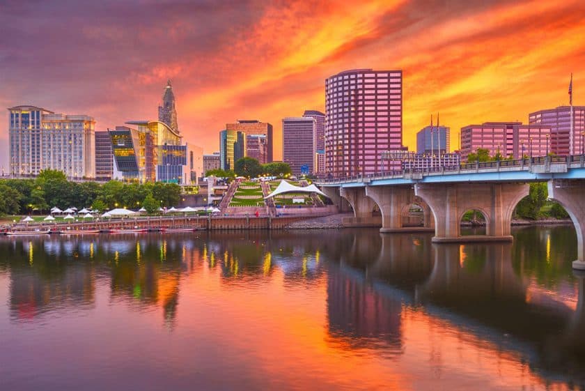 Vibrant sunset over a cityscape with reflection on a river, featuring modern buildings and a bridge in our service area.