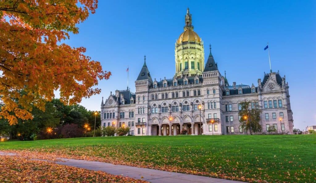 A grand building with a golden dome stands on a lush lawn, framed by autumn trees with orange leaves, embodying the same reliability and excellence as Managed IT Services Connecticut.
