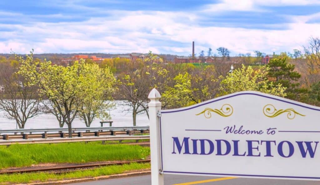 Welcome to Middletown" sign in front of a scenic view with a river, trees, and a cloudy sky in the background—a perfect blend of nature and modern amenities like managed IT services in Middletown CT.