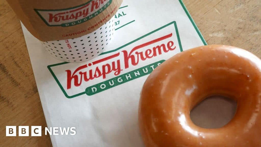 A Krispy Kreme coffee cup sits on a branded paper bag next to a glazed doughnut, while the buzz about the Sophos XGS Firewall upgrade fills the air.