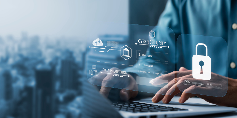 A person types on a laptop as holographic cybersecurity icons, including a padlock and data protection symbols, hover above. In the cityscape backdrop, the scene highlights Managed IT Services critical for cyber insurance readiness by 2025 through essential security measures.