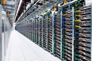 A row of server racks with numerous network cables and hardware components is organized in a brightly lit data center, highlighting the technological timeline of modern infrastructure.