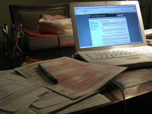 A laptop displaying the IRS website sits on a desk with tax forms, a pen, papers, and books—highlighting the importance of IRS Publication 4557 safeguarding taxpayer data.