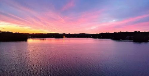 Sunset over a calm lake with vibrant pink and purple skies, reminiscent of the serene quality managed IT service in Auburn.