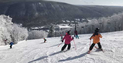 Skiers descending a snow-covered slope with a mountain landscape in the background, reminiscent of a managed IT services adventure in Bristol.