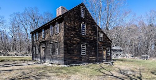 Historic wooden house with a stone foundation, located in a leafless-tree landscape under a clear sky, now serves as the headquarters for Managed IT Service Carlisle.