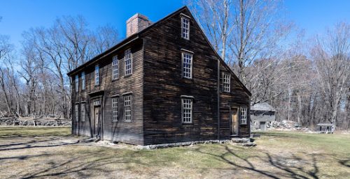 Historic wooden house with a stone foundation, located in a leafless-tree landscape under a clear sky, now serves as the headquarters for Managed IT Service Carlisle.