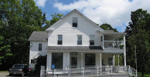 White two-story building with a balcony and a managed IT service in Chesterfield, under a partly cloudy sky.