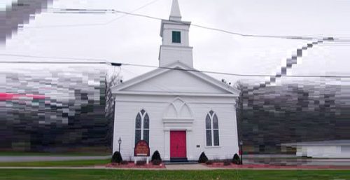 A small white church with a red door and a steeple, nestled amongst trees and under a cloudy sky, stands as timeless as the reliability of managed IT services in Columbus.