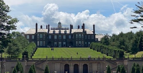 A grand estate with a large mansion atop a terraced hill, framed by manicured lawns under clear blue skies, serviced by the renowned managed IT service in Ipswich.