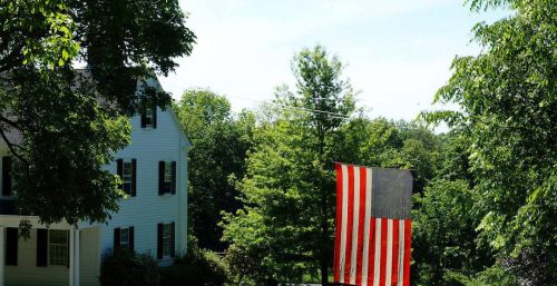An American flag flies proudly in front of a house.