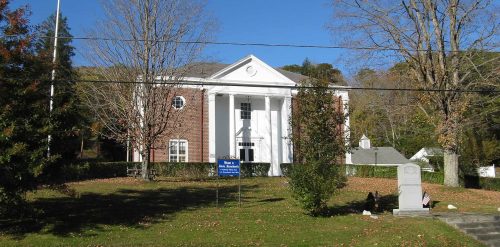 A white building with a flag pole in front of it, located in Monroe.