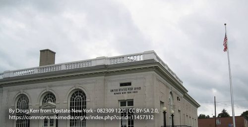 A historical post office building under a cloudy sky, featuring classical architecture with a white flagpole and an American flag in front, stands as a testament to the past even as modern conveniences like managed IT services in Newark make their presence felt.