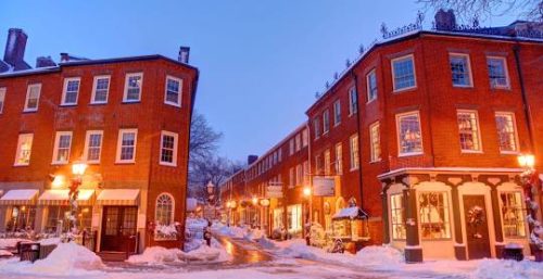 Historic brick buildings line a snow-covered street at twilight near the managed IT service in Newbury.