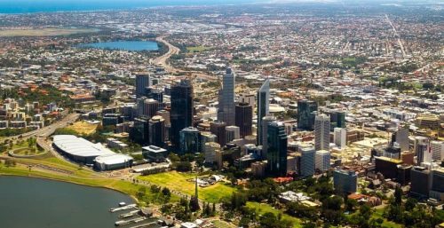 Aerial view of a modern city skyline with buildings near a river and coastal area, highlighting the location of managed IT services in Perth.