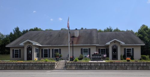 Single-story building with a central entrance flanked by symmetrical windows, managed IT services in Providence, an American flag out front, and a clear blue sky in the background.