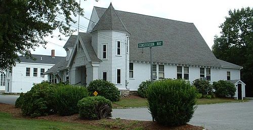 A white church with a steeple standing in front. A white church with a steeple standing in front.