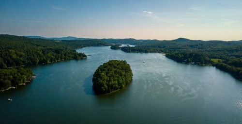 Aerial view of a serene lake with forested islands and surrounding greenery, resembling the tranquility one might find away from the bustling world of managed IT services in Salem.