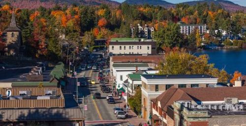 An aerial view of a small town with a mix of buildings, cars on the road, trees with autumn foliage, and hills in the background, effortlessly blending modern amenities—including managed IT services in Wilmington—into its picturesque landscape.